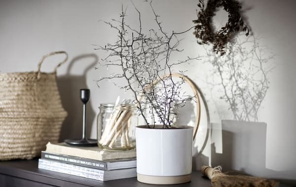 Dessus de buffet avec décorations et rangement/exposition: panier en rotin, livres, bougeoir et plante en pot.