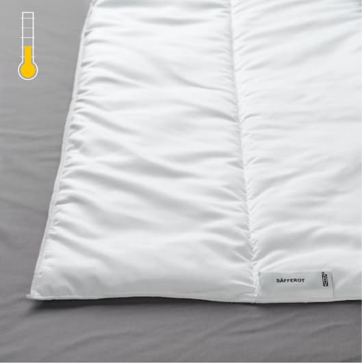 Detalle de una cama, se muestra en primer plano un edredón SÄFFEROT y en la esquina superior izquierda un termométro ''tibio''.'.