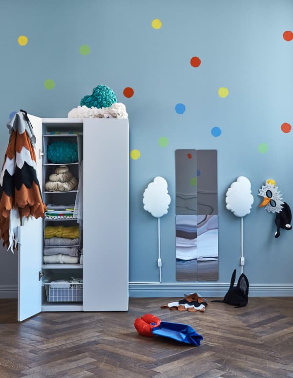 Deux appliques en forme de nuage placées de chaque côté d’un miroir et d’une armoire-penderie dans une chambre d’enfant