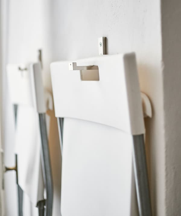 Deux chaises pliantes blanches accrochées au mur.