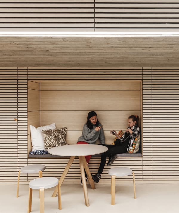 Deux femmes assises dans une niche d'un mur lambrissé, derrière une table et des chaises.