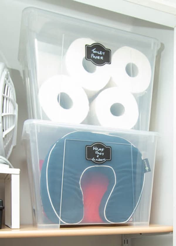 Deux grands bacs avec couvercle SAMLA transparents contenant rouleaux de papier hygiénique et autres articles variés.