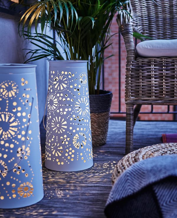 Deux lanternes métalliques à énergie solaire éclairent le balcon le soir.