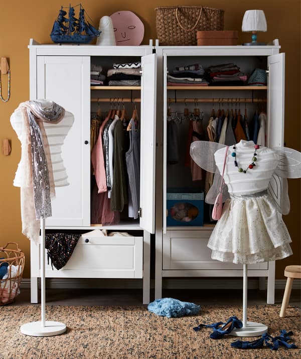 Deux mannequins partiellement habillés placés devant deux garde-robes remplies de vêtements.