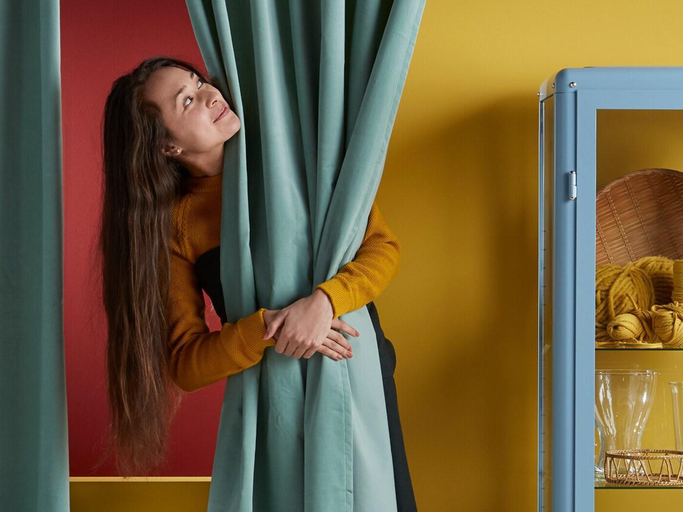 Devojka grli zavesu u izložbenom prostoru robne kuće IKEA