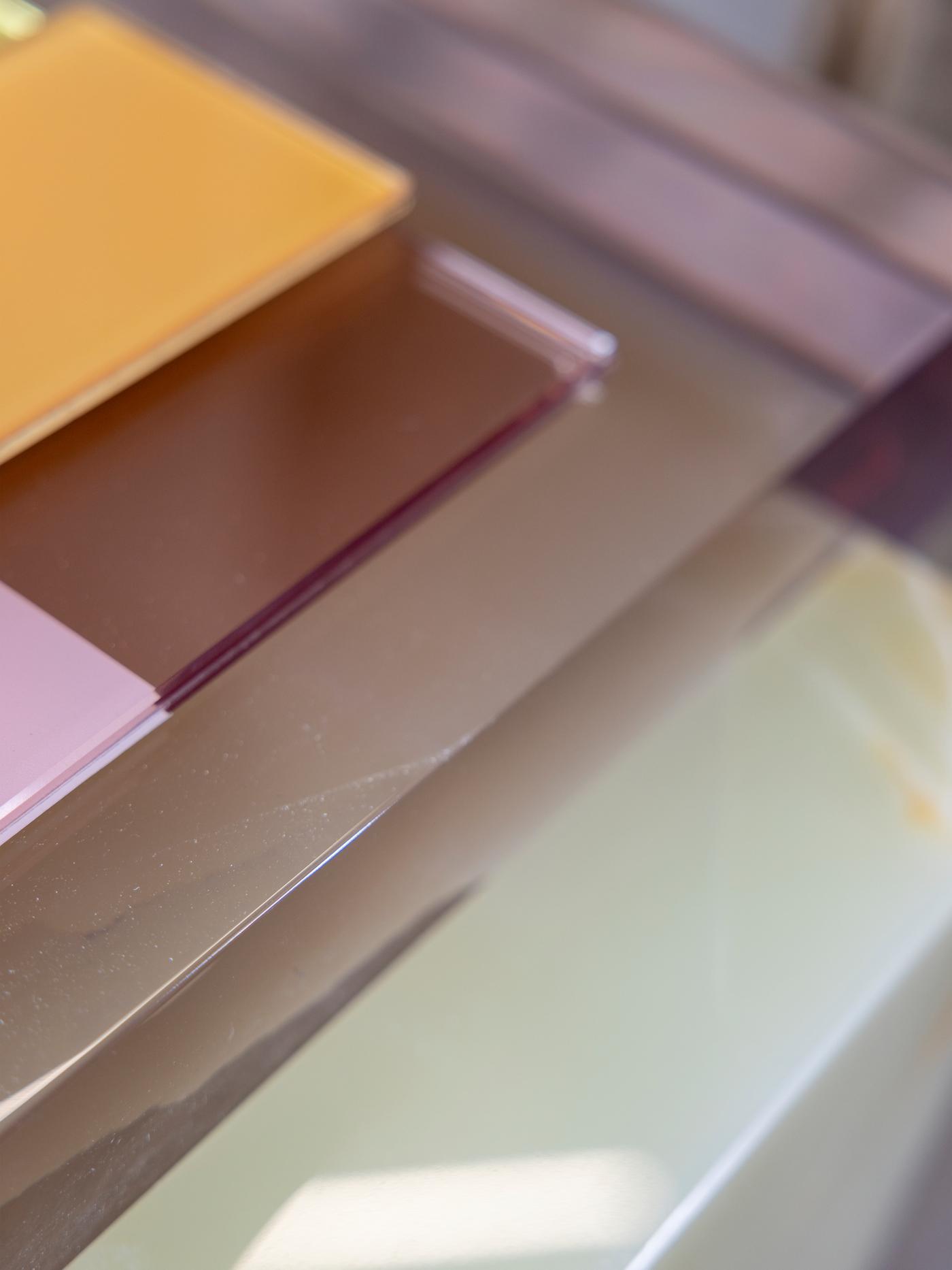 Different sheets of coloured glass are stacked on top of each other.