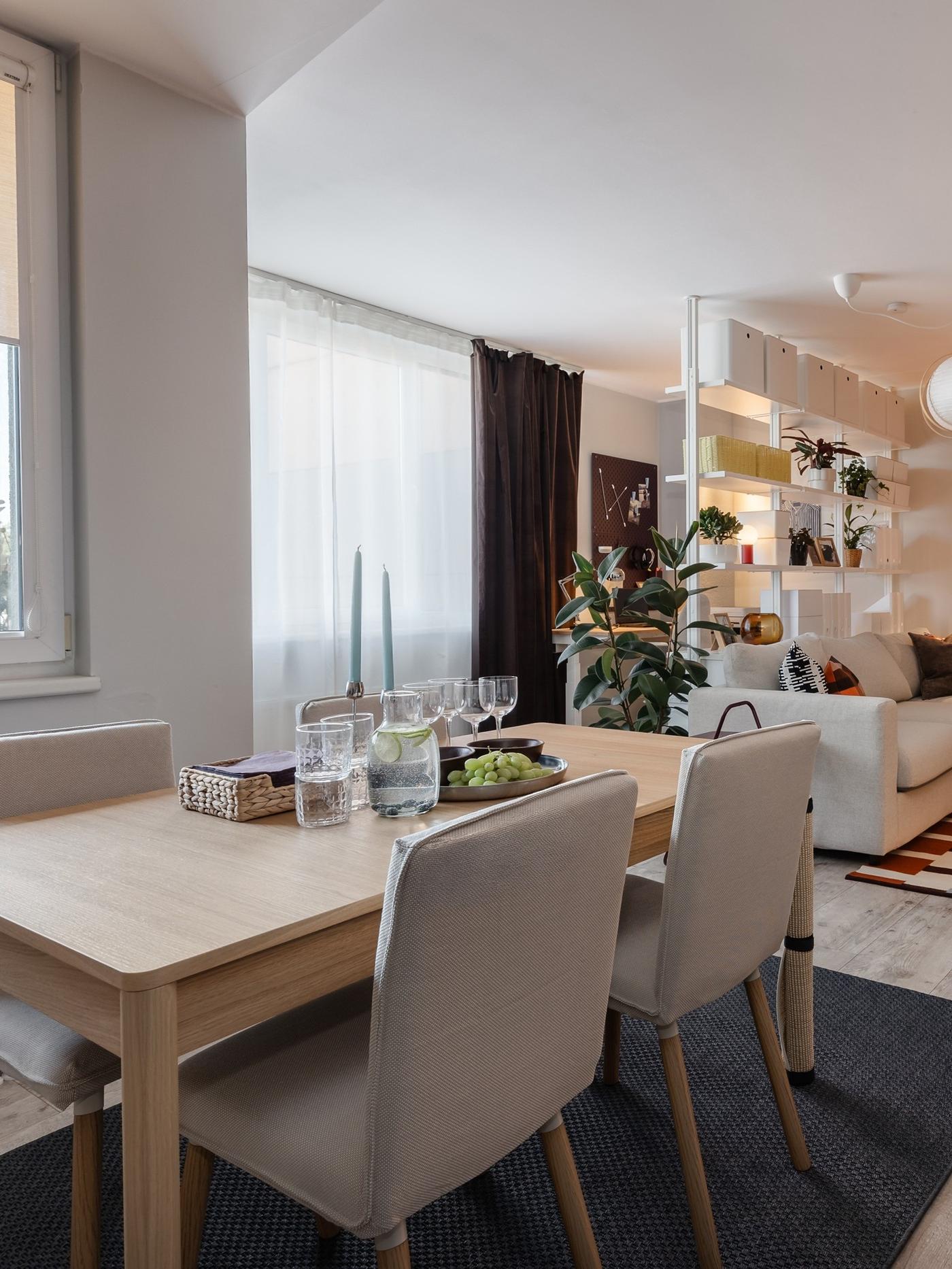Dining area with a wooden table and four upholstered chairs, overlooking the bright, open-plan living room.