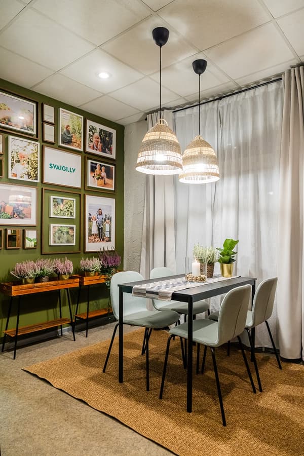 Dining area with framed photo wall, woven pendant lights, and green accent wall