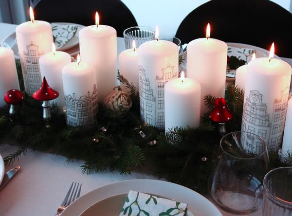 Dix bougies blanches allumées avec des décorations de Noël sur une table de salle à manger
