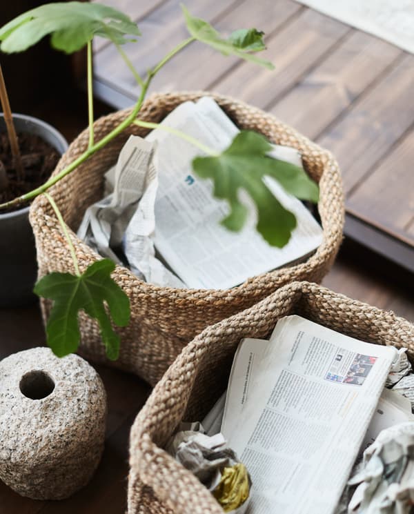 Dos canastos de yute con diarios y plantas en su interior.