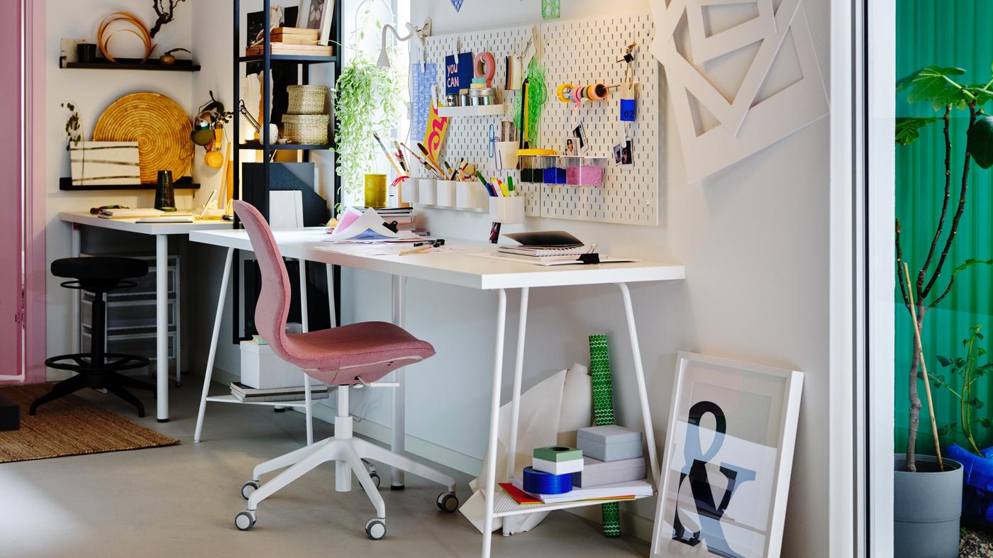Dos espacios de trabajo uno al lado del otro, uno de ellos centrado en torno a una mesa LAGKAPTEN blanca y una silla de conferencias LÅNGFJÄLL rosa.
