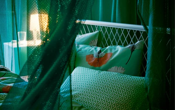 Draped green IKEA GRÅTISTEL net curtains in a bedroom, creating a room in the room, while letting through a little light