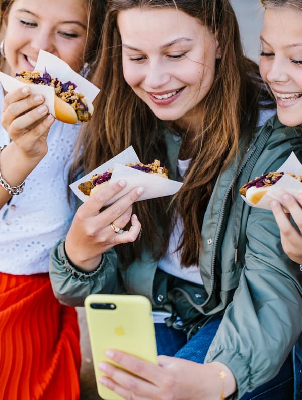 Drei Leute machen ein Selfie mit ihren Veggie-Hotdogs.