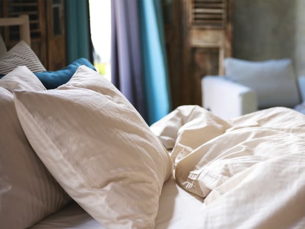 Du linge de lit en satin beige clair sur un lit dans une chambre à coucher.