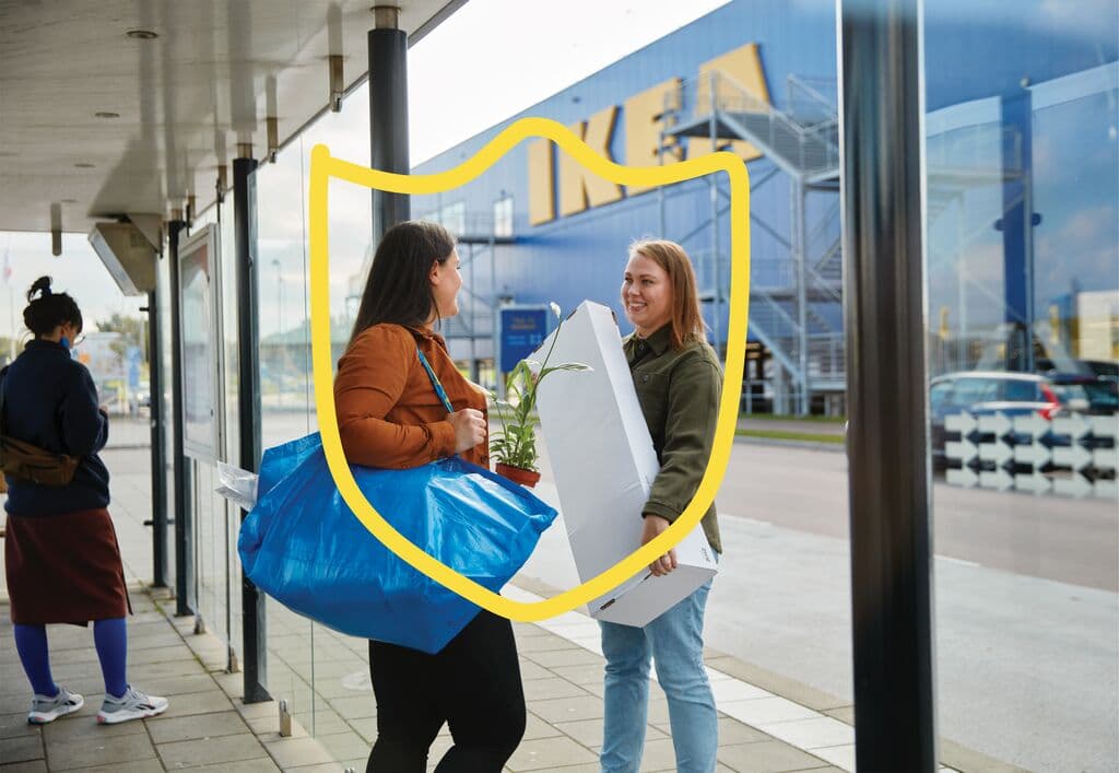 Due donne si trovano e chiacchierano tra loro davanti a un negozio IKEA con i loro acquisti