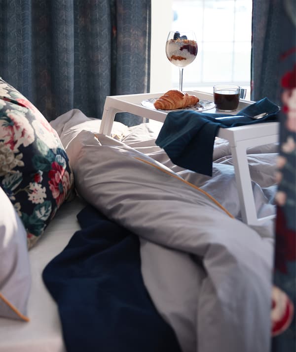 Dulang IKEA KLIPSK berwarna putih menjadi alas sarapan mewah, ketika berada di atas katil yang gebu.