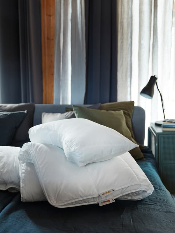 Duvet SMÅSPORRE dan bantal ergonomik SKOGSLÖK ditindan bersama di atas katil berwarna biru di dalam bilik tidur berwarna biru.