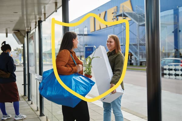 Dva lidé stojí před obchodem IKEA a oba mají nákupní tašky.