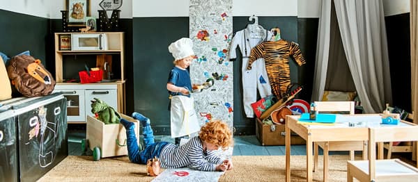Dvě děti, které si kreslí v obývacím pokoji mezi hračkami a hrami z IKEA.