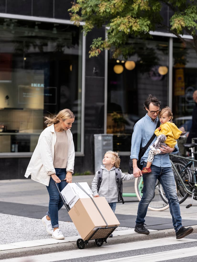 Een gezin met twee kleine kinderen steekt de straat over met IKEA dozen.