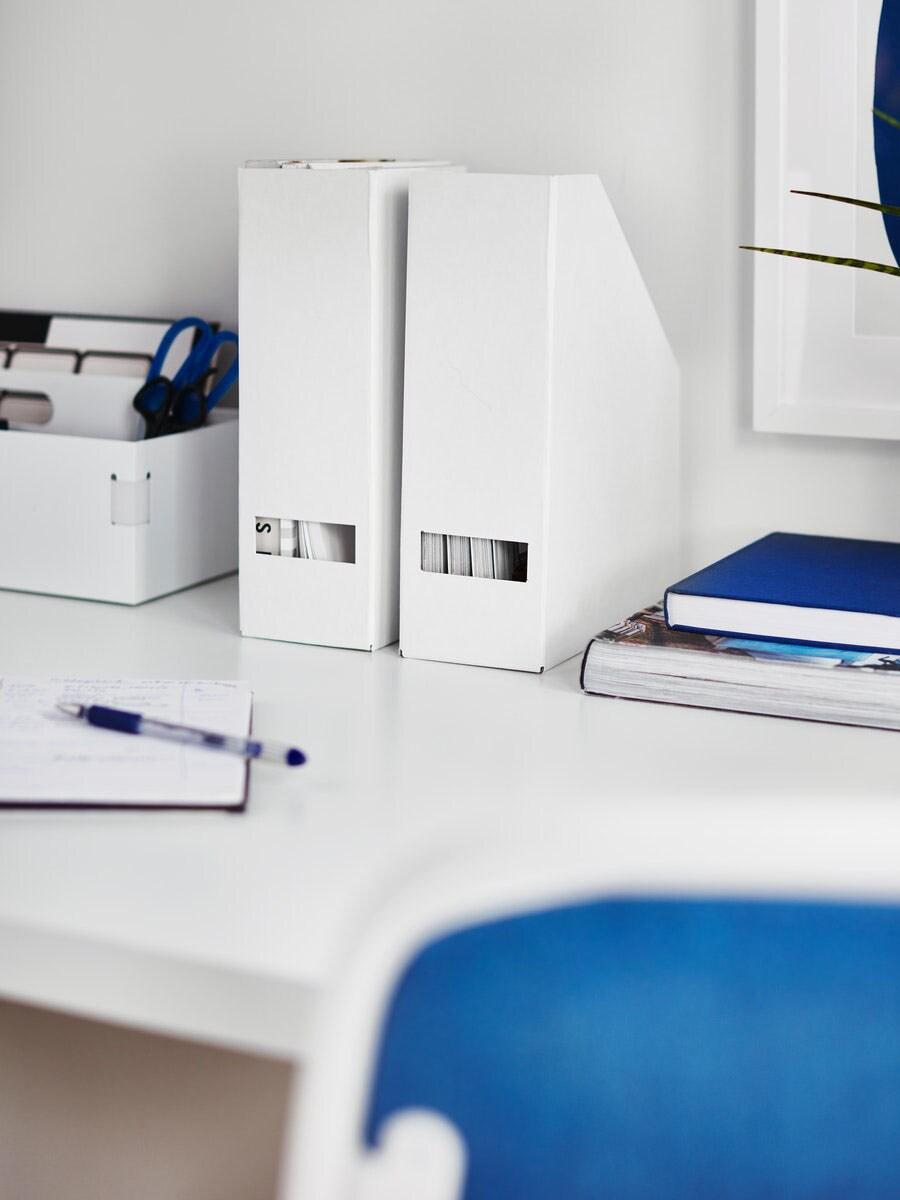 Een opgeruimd wit bureau met ordners, schrijfwaren en boeken