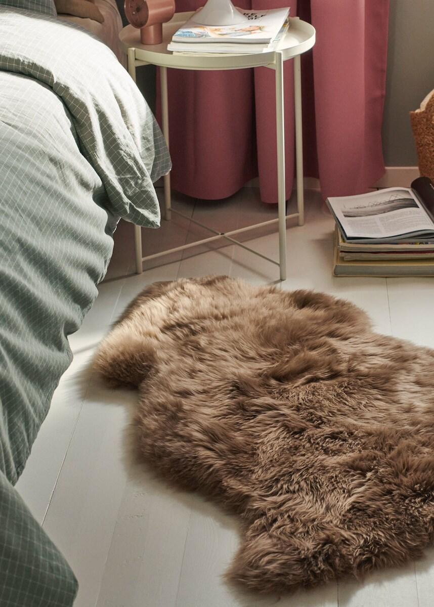 Een ULLERSLEV schapenvacht ligt naast een bed. 