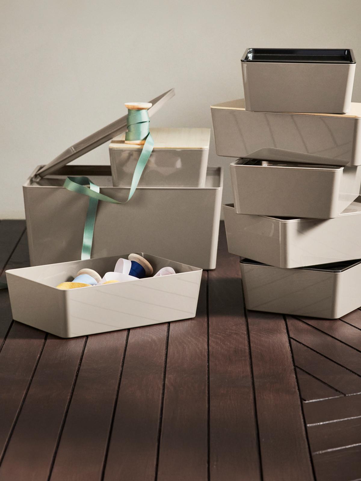 Eight KUGGIS plastic storages boxes stacked on top of each other on a brown wooden floor as Christmas gifts