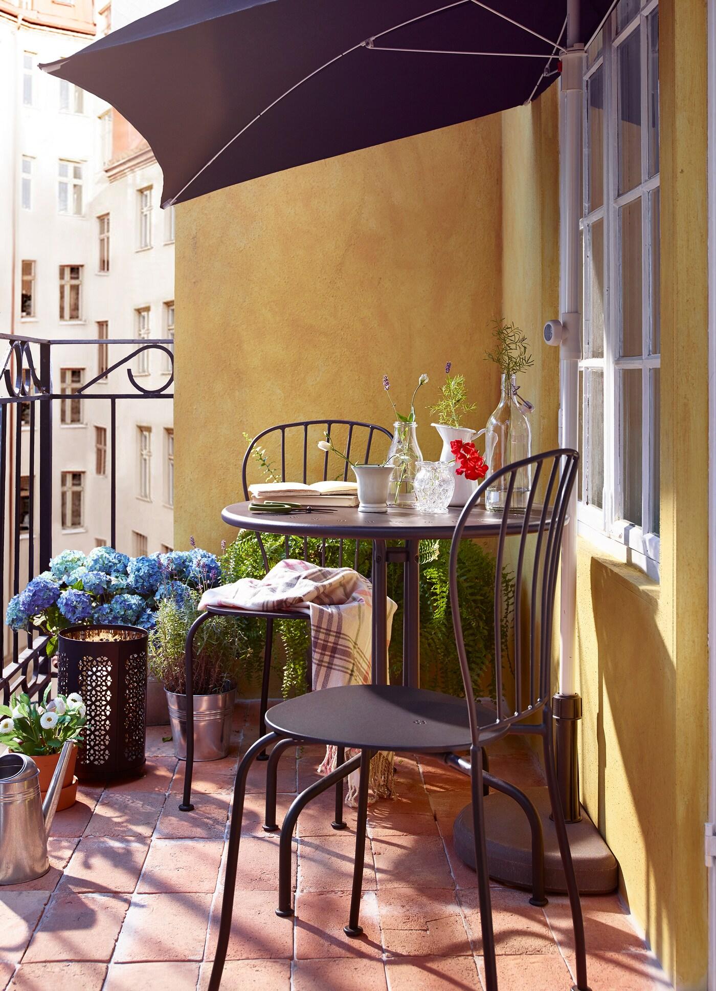 Ein Balkon mit schwarzen Balkonmöbeln aus Metall