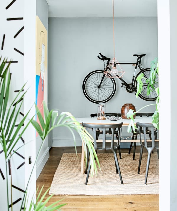 Ein Essplatz mit Tisch und IKEA PS 2012 Armlehnstühlen. Drumherum sind Pflanzen und an der Wand ein hängendes Fahrrad zu sehen.
