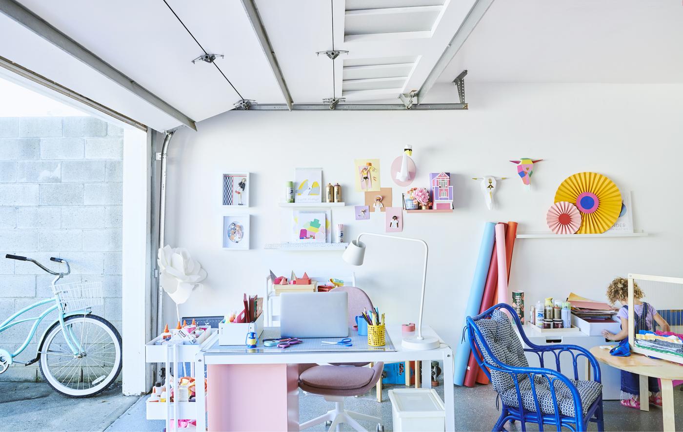 Ein farbenfroher Arbeitsplatz in einer Garage mit Schreibtisch, Servierwagen, Stühlen und Präsentation an der Wand.