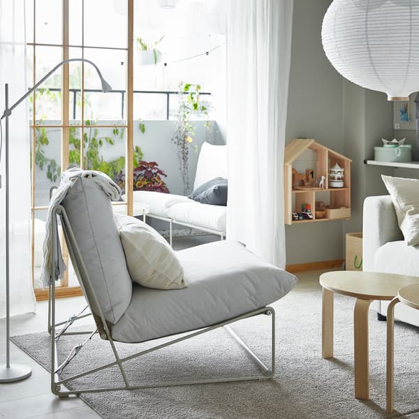 Ein HAVSTEN Sessel in einem Wohnzimmer, das sich zum Balkon öffnet – Der Sessel und das Sofa lassen sich drinnen wie draußen nutzen.