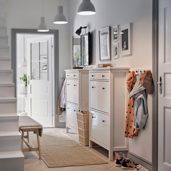 Ein heller Flur mit zwei HEMNES Schuhschränken in Weiss und vielen Haken