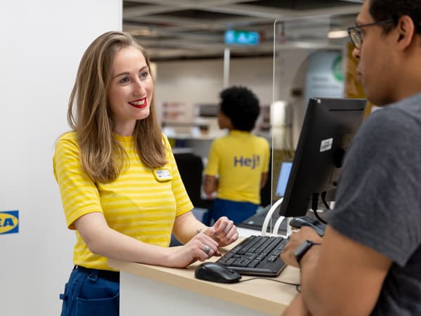 Ein IKEA Mitarbeitender scannt ein Produkt einer IKEA Kundin.