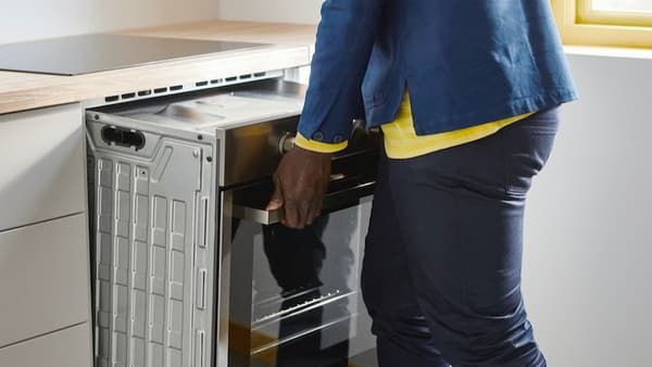 Ein IKEA Mitarbeiter, der ein E-Geräte Reparaturservice durchführt