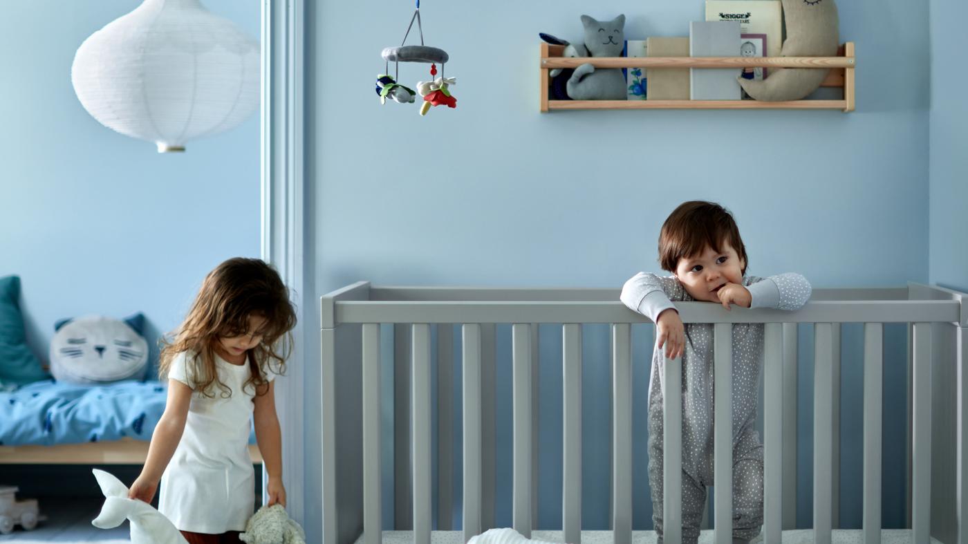 Ein Mädchen und ein Junge befinden sich in einem blau gestalteten Schlafzimmer.