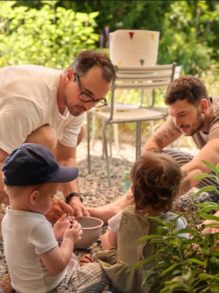 Ein männliches Pärchen spielt mit den Kindern im Garten.