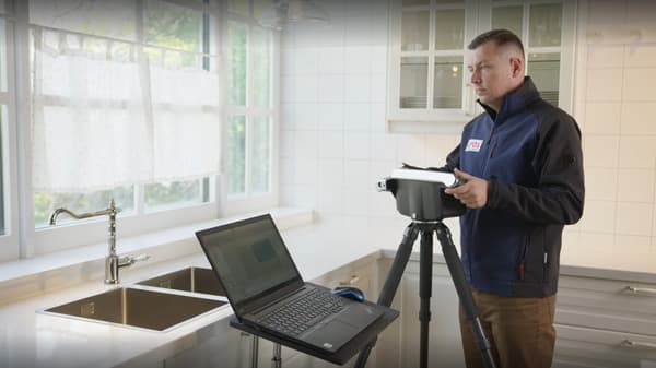 Ein Mitarbeiter misst eine Küche mit einem modernen 3D-Laser-Ausmess-System aus