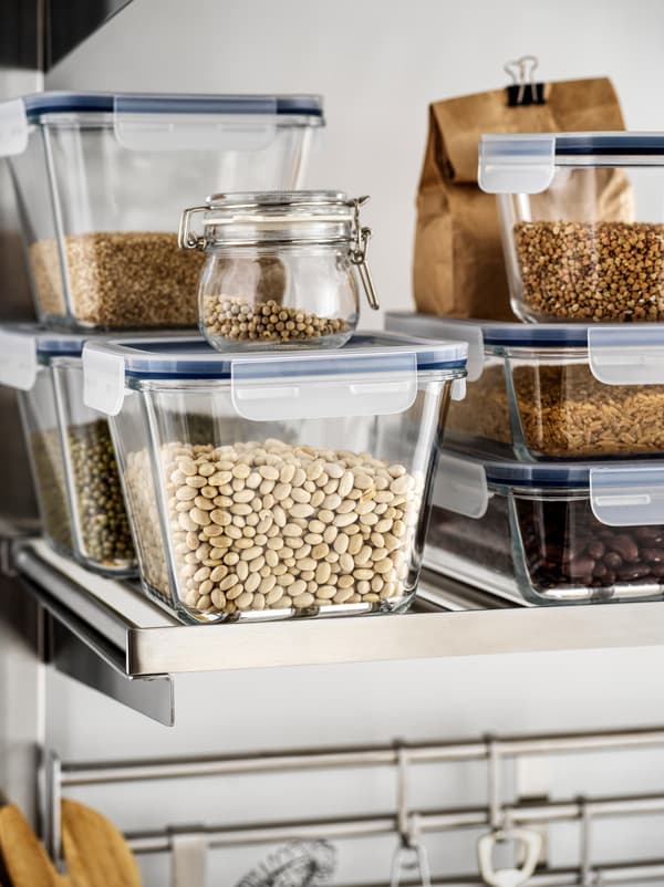 Ein offenes Küchenregal mit transparenten IKEA 365+ Lunchboxen, gefüllt mit Bohnen und übereinander gestapelt.