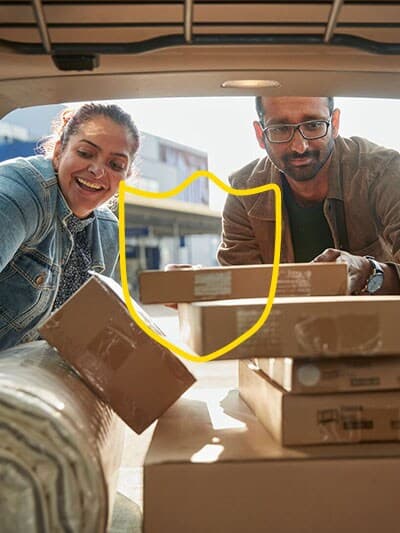 ein Paar das soeben den Kofferaum mit IKEA Kartons befüllen.