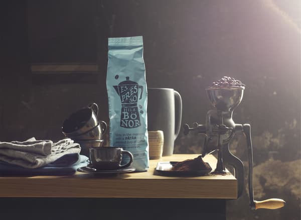 Ein Paket Kaffee, Becher und eine traditionelle Kaffeemühle, gefüllt mit Kaffeebohnen.