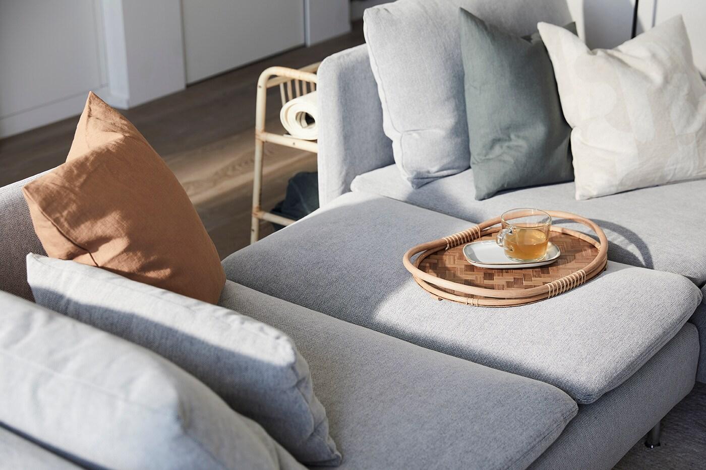 Ein Rattantablett auf einem hellgrauen Sofa 
