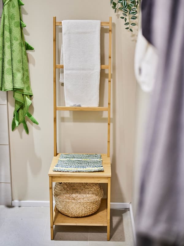 Ein selbst gewebtes Stitzkissen liegt in einem Badezimmer auf einem kleinen Regal auf das man sich drauf setzten kann.