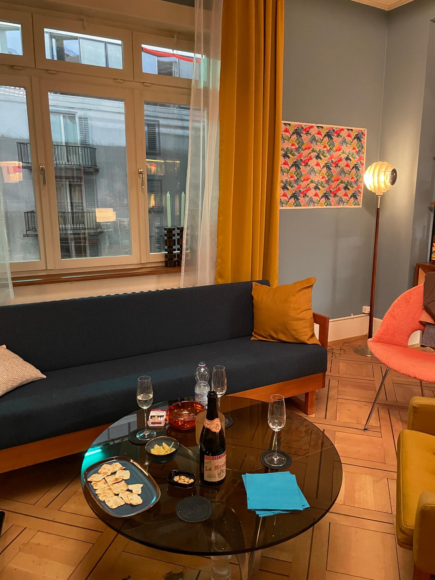 Ein Sofa mit einem runden Couchtisch davor steht vor einem grossen Fenster mit langen Vorhängen