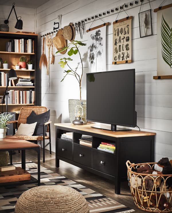 Ein traditionell eingerichtetes Wohnzimmer mit einer TV-Bank und einem Bücherregal in massiver schwarzbraun gebeizter Kiefer und Dekogegenständen aus natürlichen Materialien