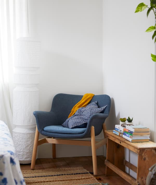 Ein VEDBO Sessel, Gunnared blau in einem weiss gestalteten Zimmer neben einer Wandleuchte.