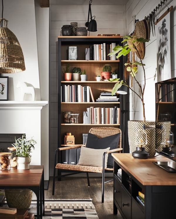 Ein Wohnzimmer mit einer TV-Bank und einem Bücherregal in massiver schwarzbraun gebeizter Kiefer, einem Sessel aus Rattan und anderen Gegenständen aus Naturmaterialien