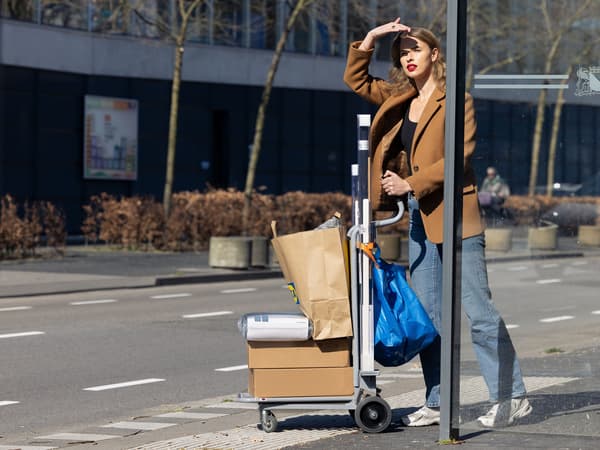 Eine Dame, die mit einem ausgeliehenen Transportwagen mit IKEA Produkten, durch die Stadt geht.