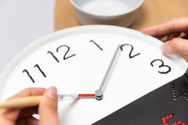 Eine Frau montiert die Uhr Zeiger in der Mitte der Uhr.