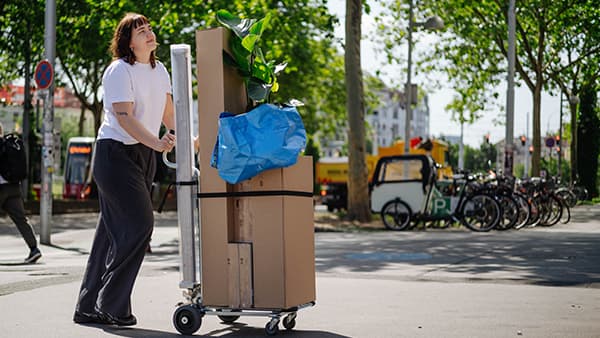 Eine Frau schiebt einen vollbeladenen Transportwagen durch die Straßen Wiens.