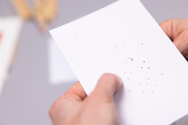 Eine Frau sticht mit einem Faden durch ein Paier